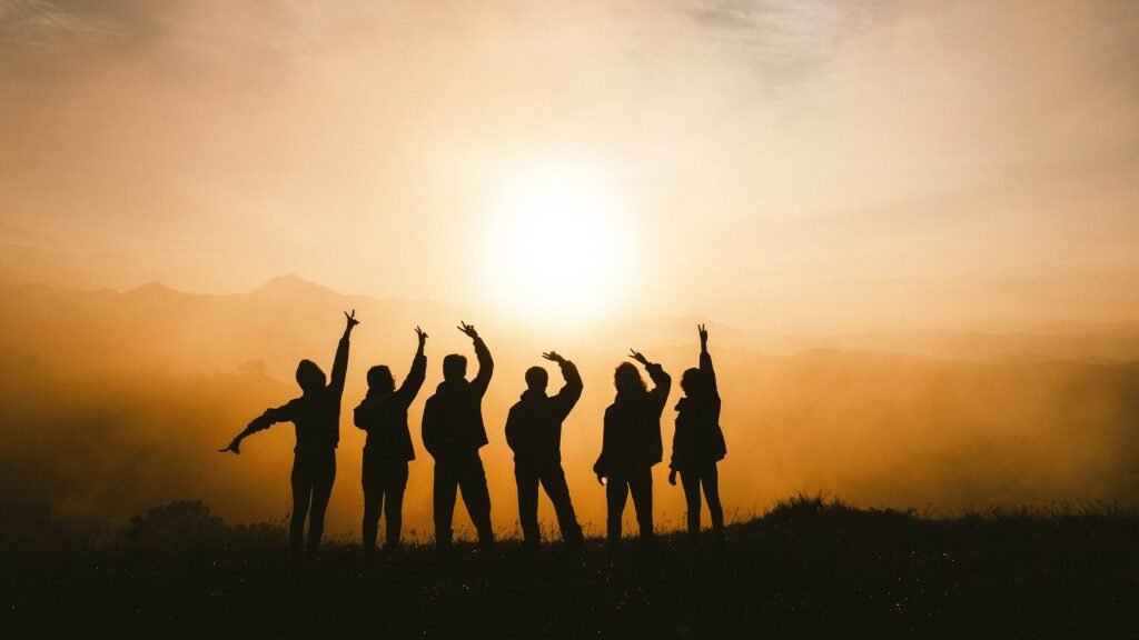 Silhouette of a group of teenagers on a mountain top.